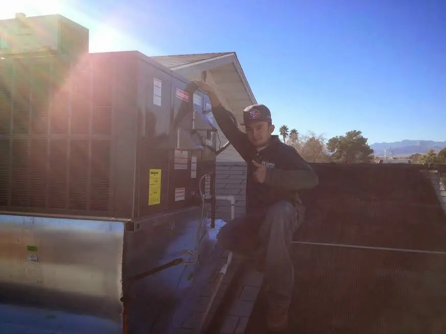 HVAC technician performing AC Tune-Up on a rooftop unit in Paris